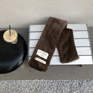 Soft brown plush winter faux fur scarf detail showcasing cozy ribbed texture and stylish fabric label.
