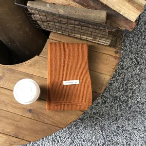 Gemütlicher warmer Strickschal für den Winter in Braunton mit dekorativem Etikett.