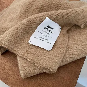 Detailaufnahme eines Strickschals mit Vintage-Stoffetikett, weich dick für warme Wintertage.