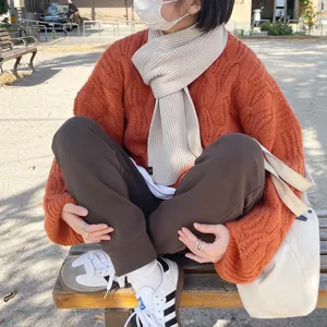 Détail d'écharpe en tricot beige pour l'hiver, texture douce et confortable pour saison.