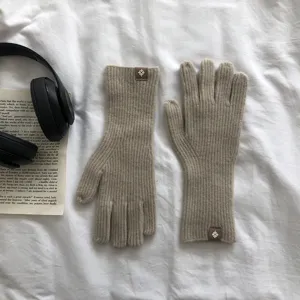 Detailaufnahme von gerippten Strick-Touchscreen-Handschuhen in Beige mit Logopatch.