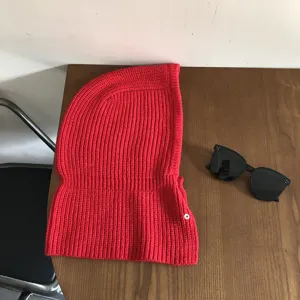Red knitted balaclava hat detail shot, showing textured rib knit fabric and snap button.