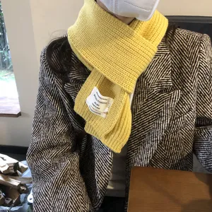 Gelber Strick Winterschal Detail mit schickem Stoffetikett und weichem Wollmaterial.