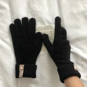 Nahaufnahme von schwarzen Winter-Wollstrickhandschuhen mit Touchscreen-Fingerspitzen und Label.