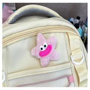 Primo piano dettagliato del grazioso ciondolo stella di peluche rosa sullo zaino beige.