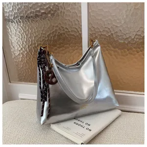 Silver metallic underarm shoulder bag, stylish casual handbag detail view with chic pendant.