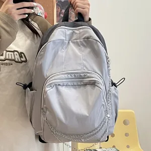 Casual grey nylon backpack for women and students with chain and pockets for daily commute.