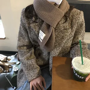 Detailansicht des braunen Strickschals mit Stoffetikett und weicher Wintertextur für Damen