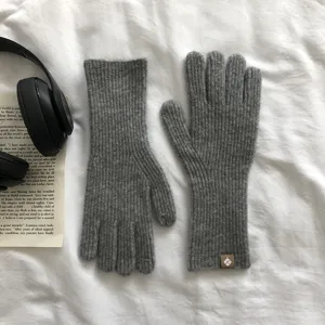 Detailaufnahme grauer Wollstrickhandschuhe mit Rippbündchen und Touchscreen-Design.