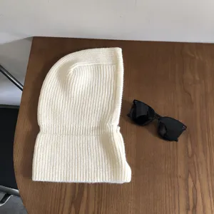 Detailed view of a cozy white knitted balaclava winter hood scarf, soft texture on wooden table.