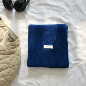 Vue détaillée d'une écharpe en tricot bleu uni pour femmes, accessoire d'hiver douillet.