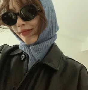 Close-up detail of the stylish blue knitted balaclava hood with snap button and leather jacket.