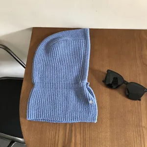 Close-up of blue knit balaclava hood scarf with snap button on wooden table.