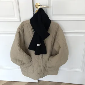 Vue détaillée d'une écharpe d'hiver en tricot noir avec étiquette blanche sur veste matelassée.