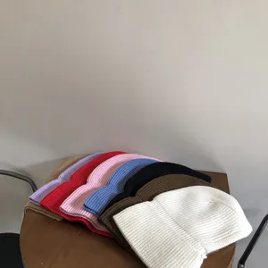 Detailed view of colorful knitted winter beanie hats neatly stacked on a wooden table.