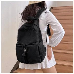 Detail shot of black denim casual backpack on model, showcasing front dual pockets and straps