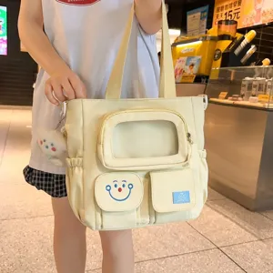 Κίτρινη τσάντα ώμου καμβά ita bag με διαφανή τσέπη και χαρούμενο χαμόγελο για μαθητές.