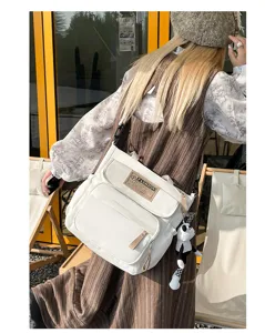 Bolso bandolera de lona blanca para estudiantes, mochila crossbody casual con bolsillos.