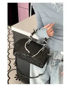 Vista detallada del bolso negro de cocodrilo con un diseño de asa de serpiente metálica.