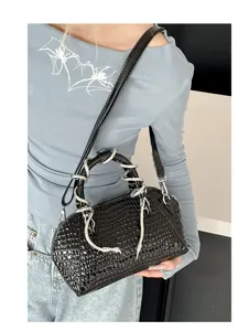 Primer plano del bolso negro con patrón de cocodrilo y asa de serpiente plateada única.