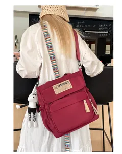 Bolso bandolera de lona burdeos para estudiantes, bolso casual con múltiples bolsillos y colgante.