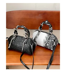 Vista detallada del elegante bolso con textura de cocodrilo y asa metálica decorativa.