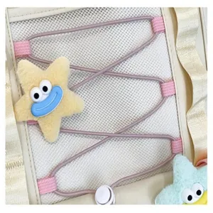 Primo piano di graziosa stella in peluche, tasca a rete e cordino viola sullo zaino beige