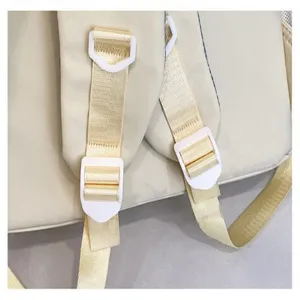 Vista dettagliata delle cinghie dello zaino beige e delle fibbie bianche regolabili.