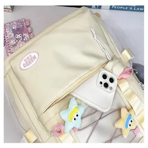 Vista dettagliata di uno zaino casual beige in tela con tasche multiple e ciondoli a stella.