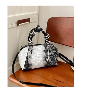 Bolso concha bicolor en blanco y negro con asa de serpiente metálica y correa elegante.