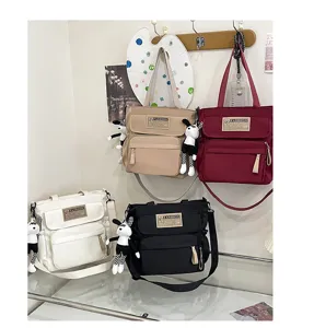 Bolso bandolera de lona para estudiantes, bolsa casual con bonitos colgantes de muñeca.