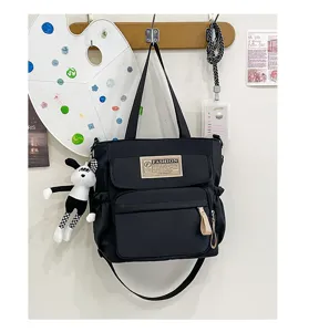 Bolso bandolera de lona negra para estudiantes, bolso casual duradero con bolsillo frontal.