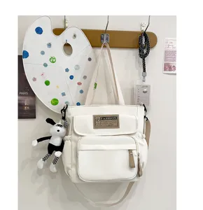 Detalle de bolso bandolera de lona blanca para estudiantes, bolso informal con bolsillos.