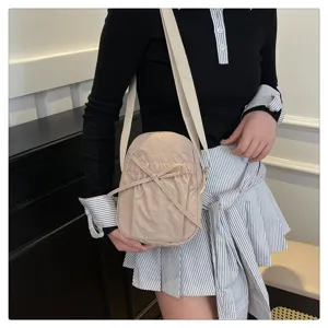 Close-up of lightweight nylon crossbody bag with cute bow drawstring and wide strap.