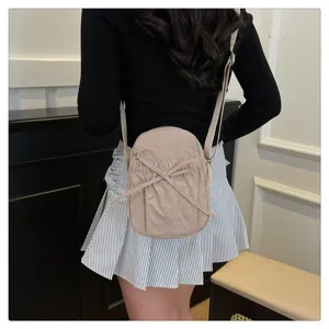 Detail view of the lightweight nylon cross-body bag featuring a cute bow and adjustable strap.