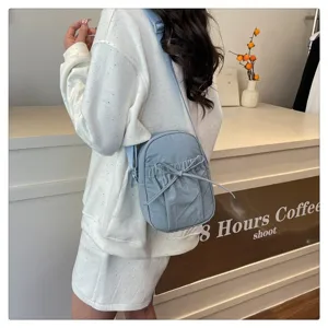 Detail view of a light blue nylon crossbody bag featuring a cute bow drawstring for women.