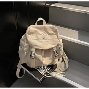 Close-up detail of a beige nylon casual backpack with drawstring and buckles on stairs.