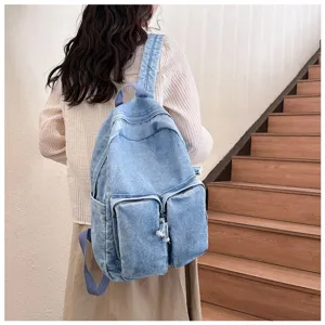Detail view of a casual retro light blue denim backpack with front pockets and comfortable straps.