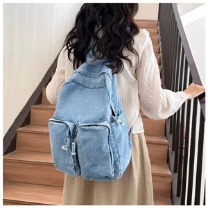 Detail view of casual denim backpack on stairs, showing front pockets and shoulder straps.