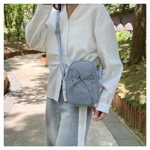 Close-up detail of the light blue nylon crossbody bag with cute bow and casual shoulder strap.