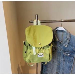 Light green minimalist oxford backpack detail view showing front label and drawstring.
