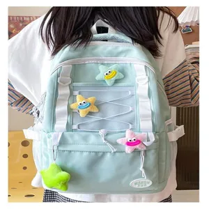Dettaglio di uno zaino casual verde menta con pendenti a stella in peluche e tasche a rete.
