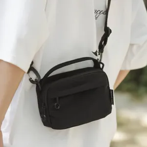 Kompakte schwarze Nylon-Umhängetasche mit Tragegriff und verstellbarem Gurt für Alltag.