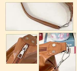 Detail view of brown patent leather shoulder bag, showing strap, metal zipper and hardware.