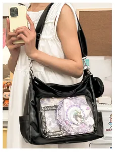 Detail shot of black PU leather Ita bag featuring transparent front window with anime badges.