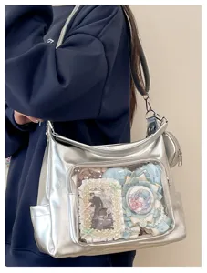 Silver metallic ita bag detail, transparent window with anime badges, casual shoulder tote.