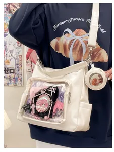 Detailed view of white PU transparent ita bag with clear window, anime badges and shoulder strap.