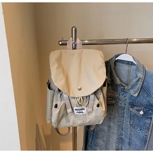 Minimalist oxford fabric backpack detail showing front flap, drawstring and branded label.