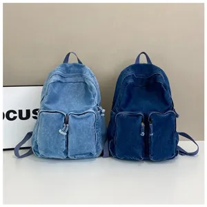 Detail view of two vintage denim backpacks featuring front pockets and washed texture.