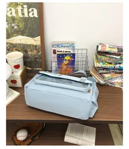 Detail view of light blue ita bag featuring clear window for badge display, student crossbody.